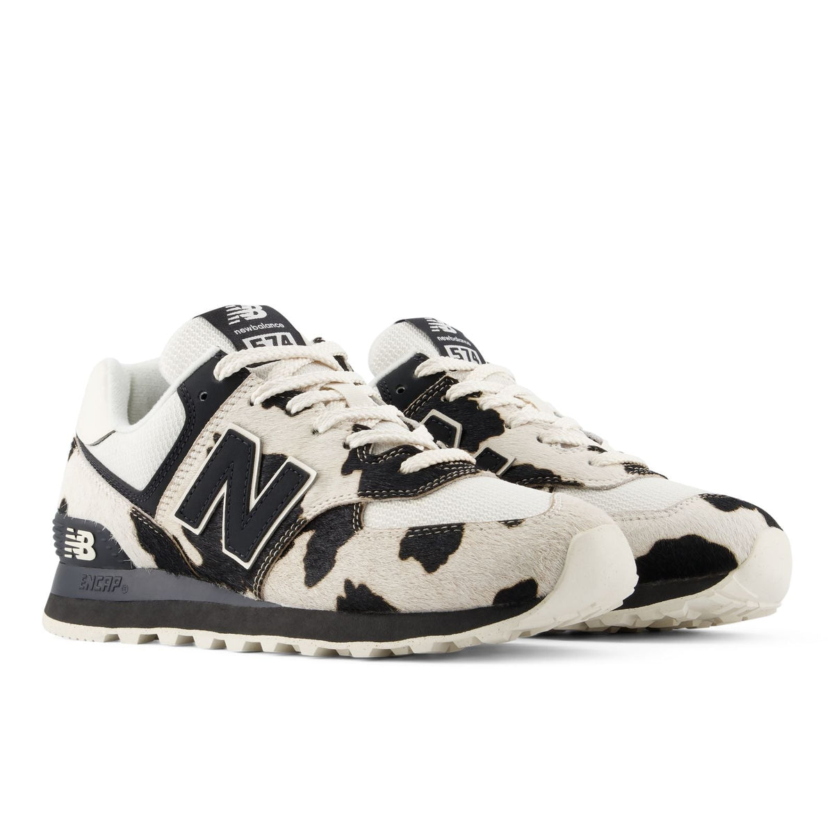 New Balance 574 Cow Print in black and cream, three-quarter view showing the calf-hair Holstein panels