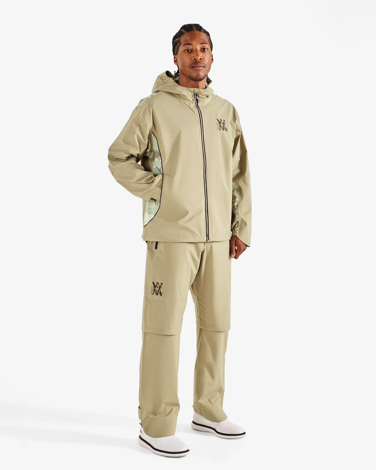 Malbon Golf x Daniel Arsham Cloudburst Rain Jacket – Dune worn on model — beige hooded full-zip rain jacket with dotted-camo panels, Gallery Streetwear Canada