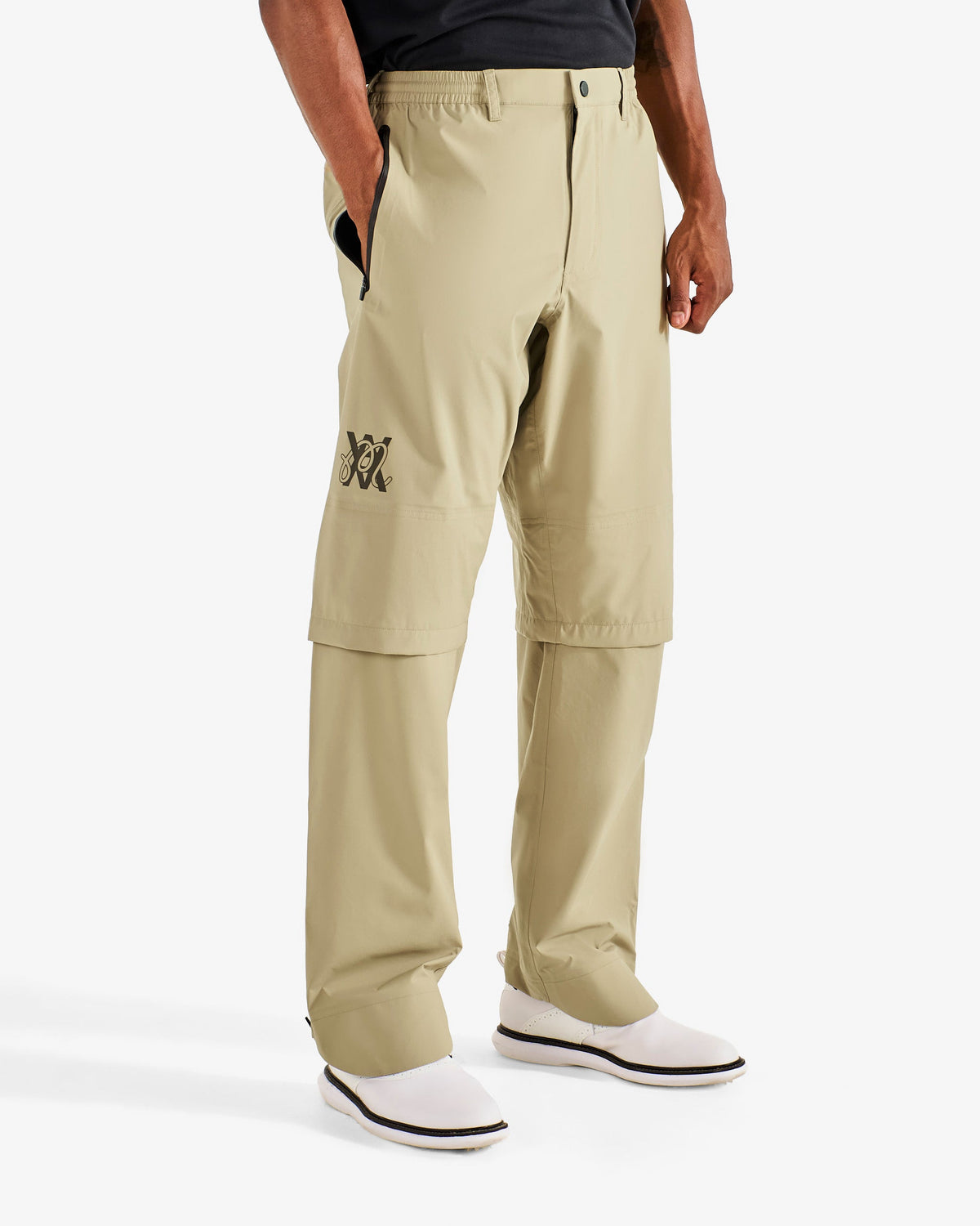 Malbon Golf x Daniel Arsham Flint Stealth Rain Pant – Dune worn on model — beige rain pant with convertible zip-off knee detail, Gallery Streetwear Canada