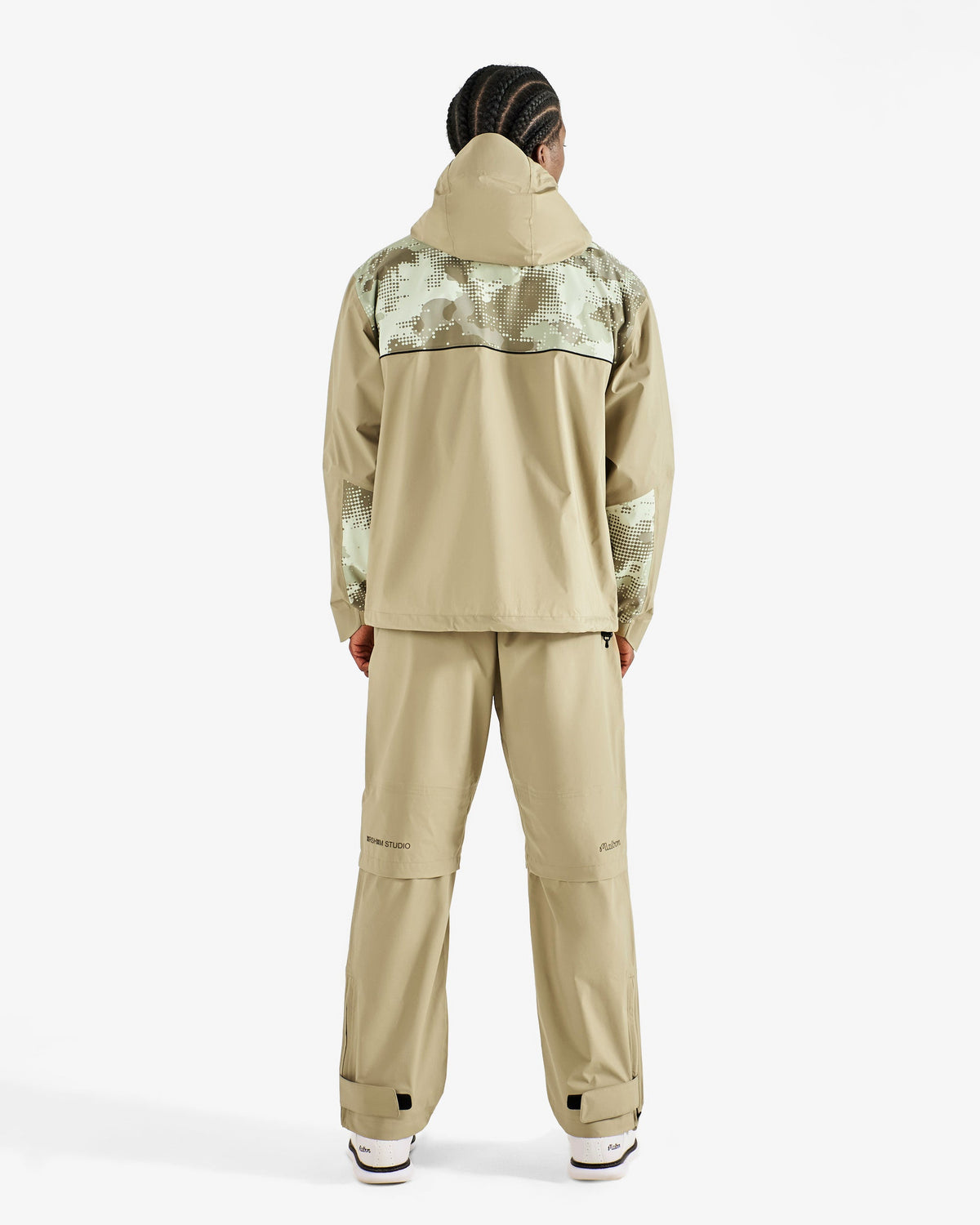 Malbon Golf x Daniel Arsham Cloudburst Rain Jacket – Dune worn on model — beige hooded full-zip rain jacket with dotted-camo panels, Gallery Streetwear Canada